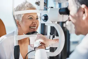 An elderly woman is getting her eyes examined by a doctor in a medical room.