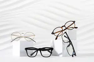 Four pairs of eyeglasses sit on white boxes against a white background