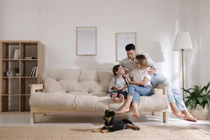 A family sitting on a sofa in the living room with a dog on the floor