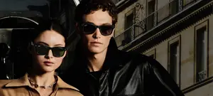 A man and a woman wearing sunglasses are standing in front of a building