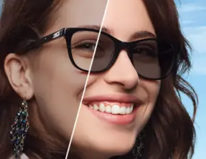 A woman wearing black rimmed glasses and a blue earring, smiling at the camera