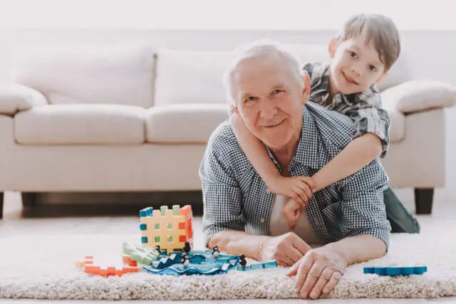 Elderly man playing with a young boy on the floor