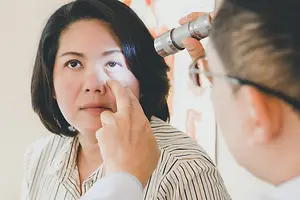 A woman has her eye examined by a male doctor