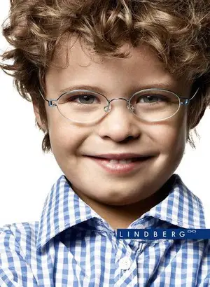 A young boy with curly hair wearing glasses and a blue and white checkered shirt with the word Lindberg on it.