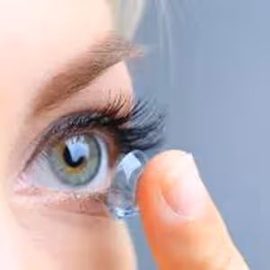 A close up of a woman's eye with a contact lens being placed on it.