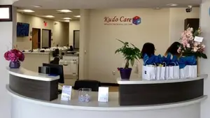 A dental clinic reception area with a curved desk, a monitor, and flowers in vases, showcasing the interior design and welcoming atmosphere of the clinic.