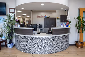 Kudo Care Center in Irving, TX, reception area with modern furniture, plants, and a monitor on the desk.