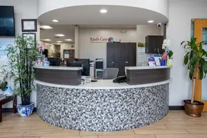 Kudo Care Center in Irving, TX, reception area with modern furniture, plants, and a monitor on the desk.
