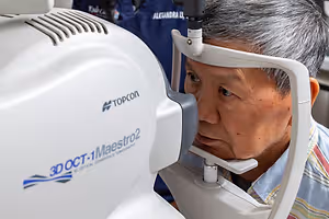 An older man is using an eye examination machine to check his eyes