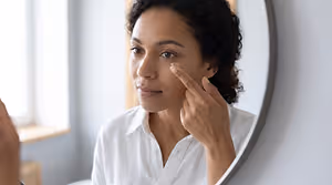 Woman applying a contact lens while looking in a mirror