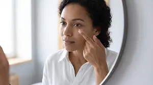 Woman applying a contact lens while looking in a mirror