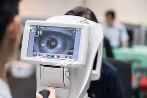 A person uses an ophthalmoscope to check a patient's eye in a blurry room