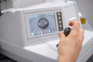 A person using a machine to measure eye pressure with a digital display showing readings