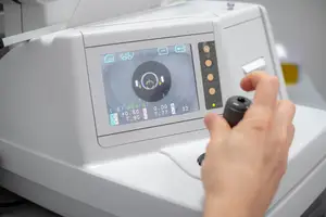 A person using a machine to measure eye pressure with a digital display showing readings