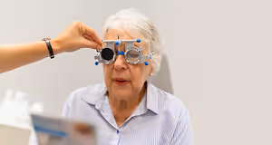 An elderly woman having her eyes checked by a healthcare professional