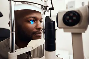 A man with blue eyes and a beard is getting his eyes checked at an eye clinic.