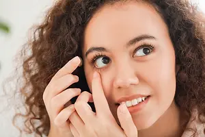 Woman with curly hair putting in contact lenses