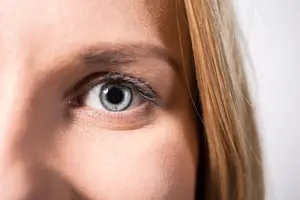 Close up of a woman's eye with blonde hair and light brown skin