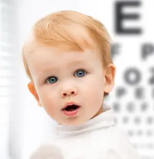 A small baby with blonde hair is looking upward in an optometrist's office.