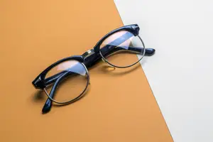 Black glasses with clear lenses on an orange and white background