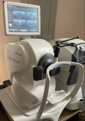 An eye exam machine with a monitor and screen is placed on a wooden table.