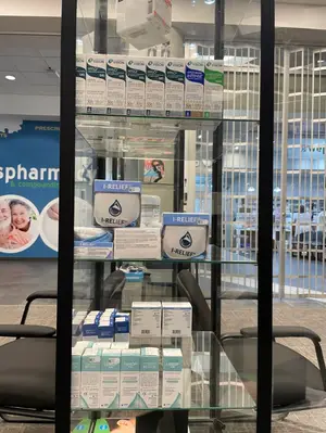 A display case in a pharmacy contains various boxes of medication, including 'I-Relief' products and other pharmaceutical items.