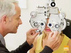 An adult male is adjusting a woman's eye exam machine in a medical clinic