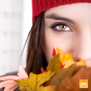 Close up of a woman's face with autumn leaves in her mouth