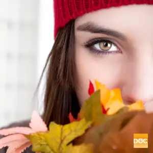 Close up of a woman's face with autumn leaves in her mouth