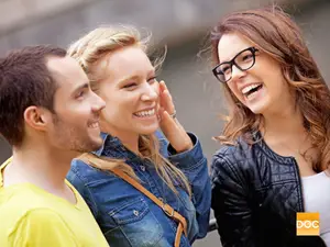Three people smiling and laughing in a city street setting