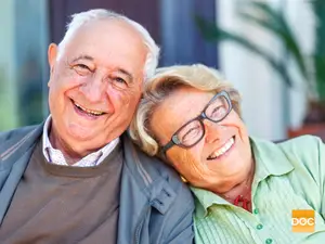 Portrait of a smiling elderly couple sitting close to each other in a living room