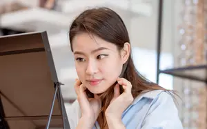 A woman is smiling and looking at a music stand with her hands on her neck.