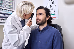 A man having his eyes checked by an optometrist in a white lab coat