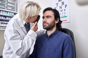 A man having his eyes checked by an optometrist in a white lab coat