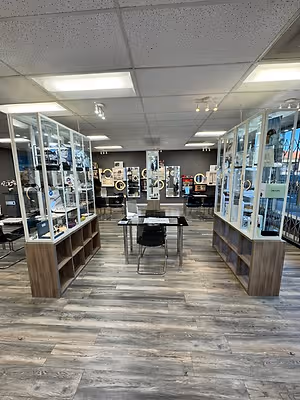 A modern jewelry store with glass display cases, wooden flooring, and ceiling lights.