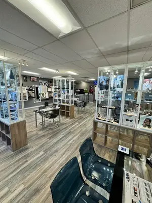 An interior view of an establishment featuring a wooden floor, glass cabinets, modern furniture, and decorative items, with a ceiling adorned with multiple lights.