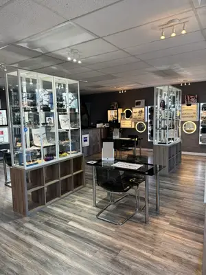 Interior of a store with a wooden floor, black desk, and glass cases displaying items.