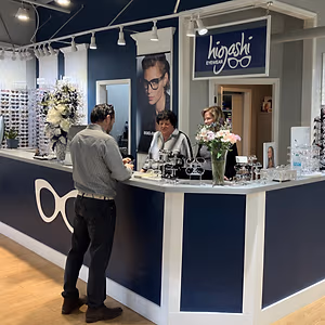 Three people standing behind a counter at Higoshi Eyewear