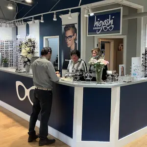 Three people standing behind a counter at Higoshi Eyewear
