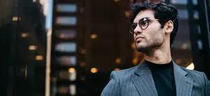 Man in sunglasses and suit standing in front of a building