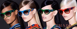 Four models wearing colorful Prada sunglasses with one model having blonde hair, another with black hair, and the other two having dark hair