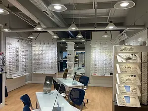 Interior of a store with tables and chairs, lamps, and shelves with glasses on display