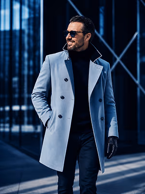 A man in a blue coat and black turtleneck is walking down a sidewalk.