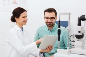 Doctor and patient looking at an ophthalmoscope in an optometrist's office.