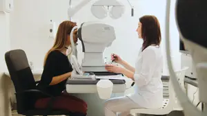 Woman at optometrist looking into machine while another woman checks her eyes