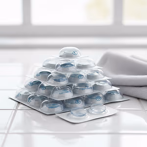 A stack of clear contact lenses with blue writing, and a white towel on the side.