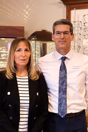 A man and a woman are standing side by side in an optical shop.