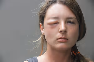 A close up of a woman with one eye closed and wearing a nose ring.