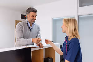 Man and woman at a hotel reception with the woman handing him a keycard