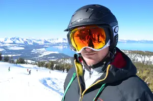 A person with a black helmet and goggles standing on a snowy mountain